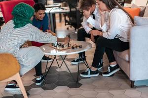 Multiethnic group of business people playing chess while having a break in relaxation area at modern startup office photo