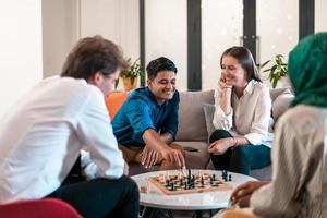 Multiethnic group of business people playing chess while having a break in relaxation area at modern startup office. Selective focus photo