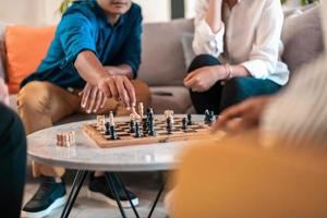 Multiethnic group of business people playing chess while having a break in relaxation area at modern startup office. Selective focus photo