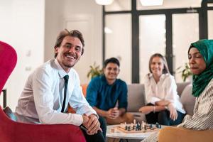 Multiethnic group of business people playing chess while having a break in relaxation area at modern startup office. photo