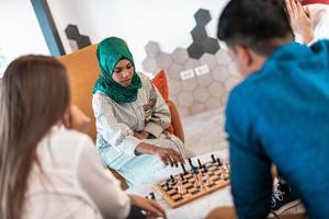 Multiethnic group of business people playing chess while having a break in relaxation area at modern startup office photo