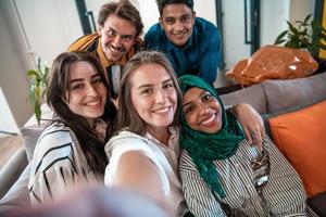 Group of business people during break from the work taking selfie picture while enjoying free time in relaxation area at modern open plan startup office. Selective focus photo