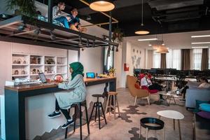 Group of casual multiethnic business people taking break from the work doing different things while enjoying free time in relaxation area at modern open plan startup office photo