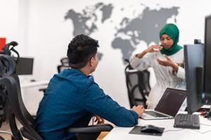 Multiethnic startup business team Arabian woman wearing a hijab on meeting in modern open plan office interior brainstorming, working on laptop and desktop computer. Selective focus photo