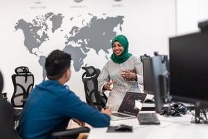 Multiethnic startup business team woman wearing a hijab on meeting in modern open plan office interior brainstorming, working on laptop and desktop computer. Selective focus photo
