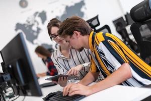 Business couple working together on project using tablet and desktop computer at modern open plan startup office. Selective focus photo