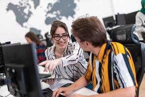Business couple working together on project using tablet and desktop computer at modern open plan startup office. Selective focus photo