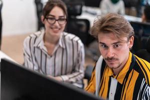 Business couple working together on project using tablet and desktop computer at modern open plan startup office. Selective focus photo