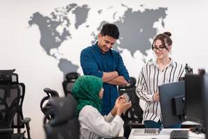 mujer multiétnica del equipo de negocios de inicio que usa un hiyab en una reunión en una moderna oficina de planta abierta con una lluvia de ideas interior, trabajando en una computadora portátil y una computadora de escritorio. enfoque selectivo foto