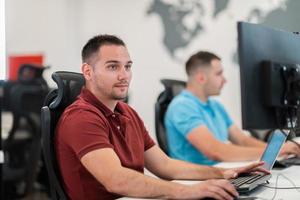 Group of Casual business man working on desktop computer in modern open plan startup office interior. Selective focus photo