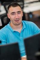 hombre de negocios casual que trabaja en una computadora de escritorio en el moderno interior de la oficina de inicio de planta abierta. enfoque selectivo foto