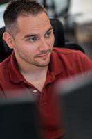 hombre de negocios casual que trabaja en una computadora de escritorio en el moderno interior de la oficina de inicio de planta abierta. enfoque selectivo foto