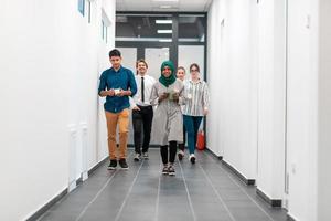 Multi-ethnic startup business team walking through the hallway of the building while coming back from a coffee break photo