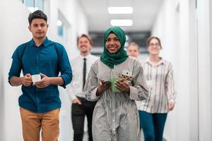 Multi-ethnic startup business team walking through the hallway of the building while coming back from a coffee break photo