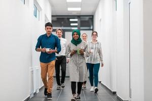 equipo empresarial multiétnico caminando por el pasillo del edificio mientras regresa de un descanso para tomar café foto