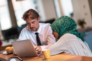 International multicultural business team.Man and muslim woman with hijab working together using smartphone and laptop coxation area at modern open plan startup officemputer in rela photo