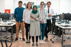 Portrait of young excited multiethnics business team of software developers standing and looking at camera at modern startup office photo