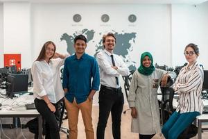 Portrait of young excited multiethnics business team of software developers standing and looking at camera at modern startup office photo