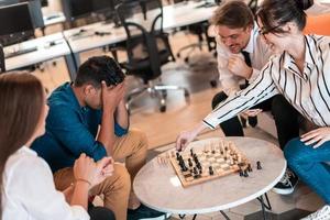 Multiethnic group of business people playing chess while having a break in relaxation area at modern startup office photo