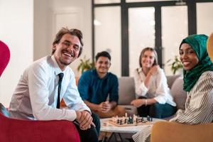 Multiethnic group of business people playing chess while having a break in relaxation area at modern startup office. photo