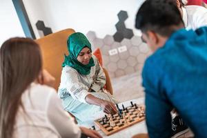 Multiethnic group of business people playing chess while having a break in relaxation area at modern startup office photo