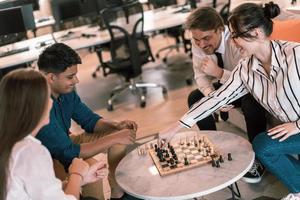 Multiethnic group of business people playing chess while having a break in relaxation area at modern startup office photo