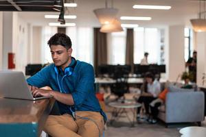 Casual business man with headphones around his using laptop for online meeting. Selective focus photo