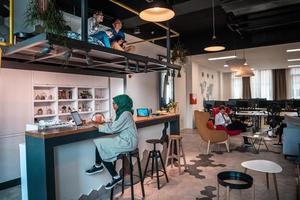 Group of casual multiethnic business people taking break from the work doing different things while enjoying free time in relaxation area at modern open plan startup office photo