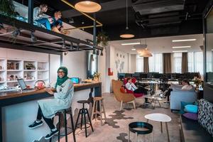 Group of casual multiethnic business people taking break from the work doing different things while enjoying free time in relaxation area at modern open plan startup office photo