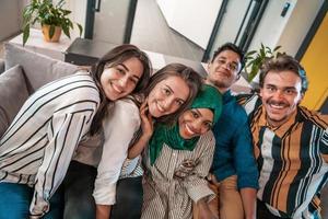 Group of business people during break from the work taking selfie picture while enjoying free time in relaxation area at modern open plan startup office. Selective focus photo