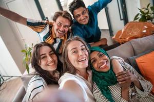 Group of business people during break from the work taking selfie picture while enjoying free time in relaxation area at modern open plan startup office. Selective focus photo