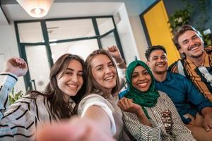 Group of business people during break from the work taking selfie picture while enjoying free time in relaxation area at modern open plan startup office. Selective focus photo