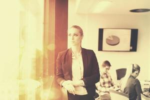 retrato de una joven mujer de negocios en la oficina con un equipo en una reunión en segundo plano foto
