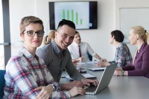 young business couple working on laptop, businesspeople group on meeting in background photo