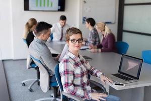 young business woman at office working on laptop with team on meeting in background photo