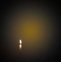 Candles were lit in the darkness to perform some rituals such as orange light. focus on the candle There is light on the background, there is orange on the black surface. photo