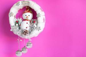 fondo navideño de muñeca de muñeco de nieve en corona de navidad suave blanca con muchas decoraciones de baratijas. foto