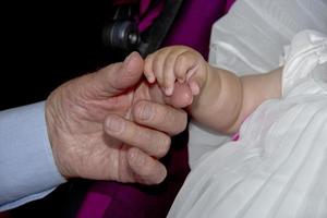 old retired man hands holding newborn infant one photo