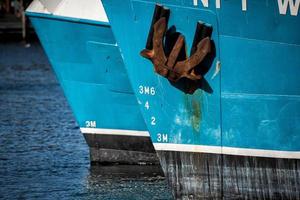 Rusted rugged Anchor on blue fishing ship photo