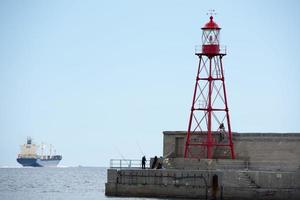 fisherman near lighthouse pier photo