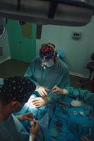 cirujano y su asistente realizando cirugía estética en la nariz foto