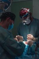 cirujano y su asistente realizando cirugía estética en la nariz foto