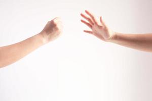 Two person playing rock paper scissors, one hand showing rock or hammer symbol and another hand showing paper symbol, concept of business competition. photo