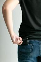 una mujer saca una billetera de dinero del bolsillo de los jeans. foto