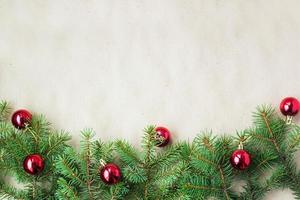 Fir tree branches decorated with red christmas balls as border on a rustic holiday background frame with copy space photo