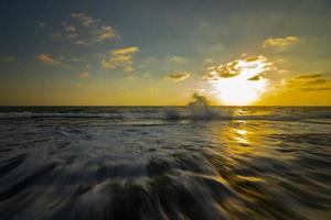 Long exposure photography of waves and pebbles on Beach in the sunset photo