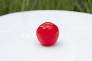 Sugar coated red cherries are used to decorate desserts in white plate. photo