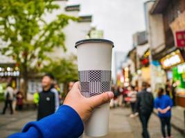 mano turística sosteniendo una taza de té con leche con un desenfoque abstracto de la calle antigua taiping en la ciudad de changsha, hunan, china foto