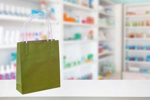 Paper bag on Pharmacy drugstore counter table with medicine and healthcare product on shelves blur background photo