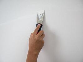 Plasterer hand repair crack white wall photo
